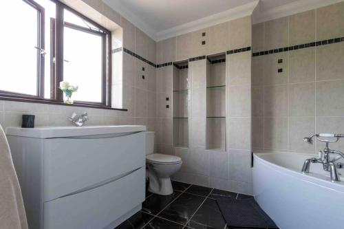 a bathroom with a tub and a toilet and a sink at Huge 6 Bed House with Entertainment room and Hotub in Southampton