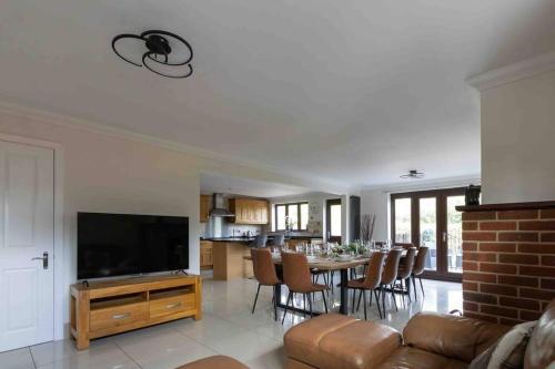 a living room with a table with chairs and a television at Huge 6 Bed House with Entertainment room and Hotub in Southampton