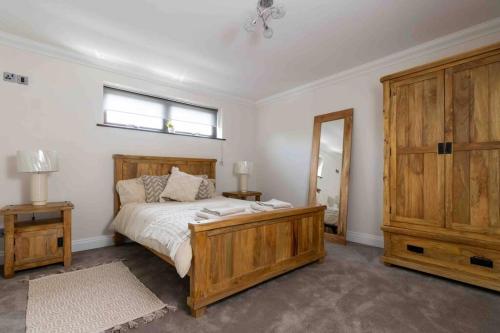 a bedroom with a wooden bed and a mirror at Huge 6 Bed House with Entertainment room and Hotub in Southampton