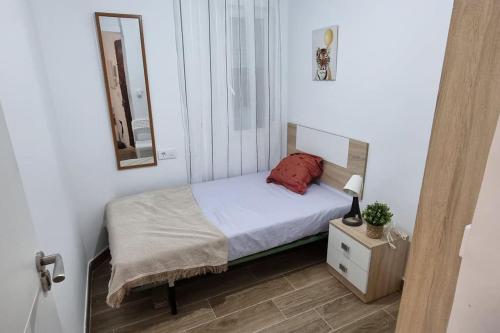 a small bedroom with a bed and a mirror at Piso amplio completo en Almería para 9 personas in Almería