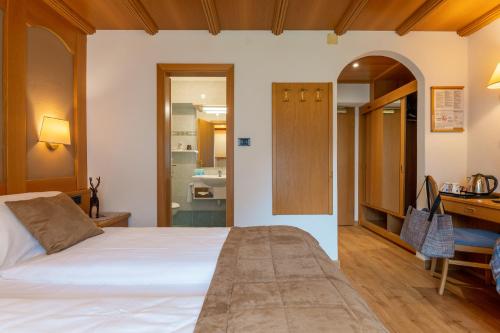 a bedroom with a bed and a desk and a bathroom at Hotel Meida in Pozza di Fassa