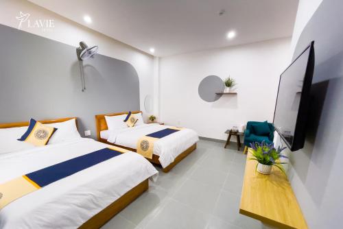 Habitación de hotel con 2 camas y TV de pantalla plana. en Khách sạn Lavie Hotel Quảng Ngãi, en Quảng Ngãi