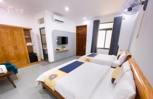 a bedroom with two beds and a tv at Khách sạn Lavie Hotel Quảng Ngãi in Quang Ngai
