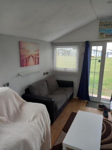 a living room with a couch and a table at Bluebell chalet in Leysdown-on-Sea
