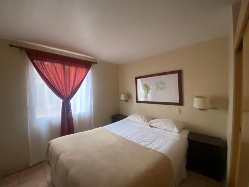 1 dormitorio con 1 cama con cortina roja y ventana en Cabañas Azapa - Caja Los Andes en Arica