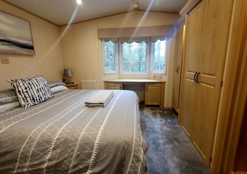 a bedroom with a bed and a desk and a window at Woodland Hot Tub Retreat in Swarland