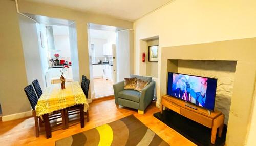a living room with a television and a dining room at Catcune Studio Suite in Gorebridge