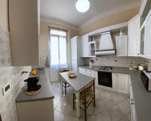 eine Küche mit weißen Schränken und einem Tisch darin in der Unterkunft La Casa dei Ricordi in Genua