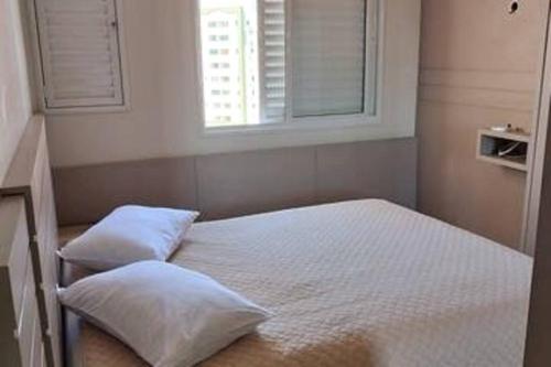 1 cama con 2 almohadas en una habitación con ventana en Apto Centro de Criciúma, en Criciúma