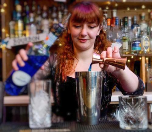 una mujer sentada en un bar mezclando una bebida en The Mad Hatter en Oxford