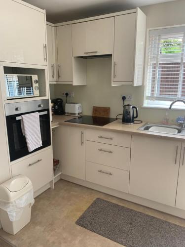 a kitchen with white cabinets and a sink at Angies Place in Midhurst