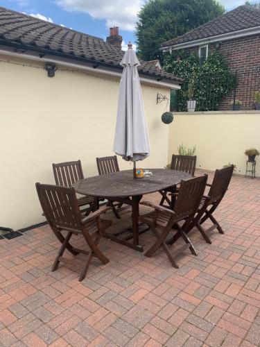 a wooden table with an umbrella and four chairs at Angies Place in Midhurst
