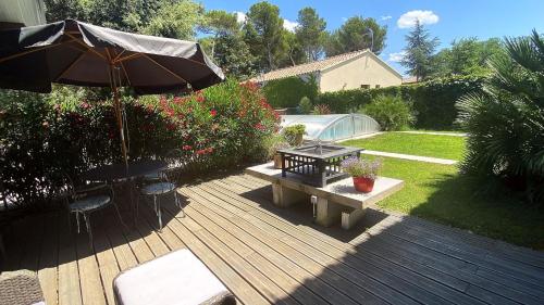 a wooden deck with a bench and an umbrella at Le Parc in Carpentras