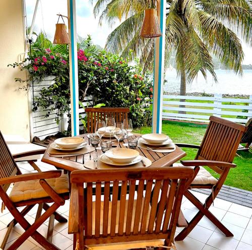 Une table et des chaises en bois sont disponibles sur la terrasse. dans l'établissement Bungalow Sucrier, les pieds dans l'eau, à Terre-de-Haut