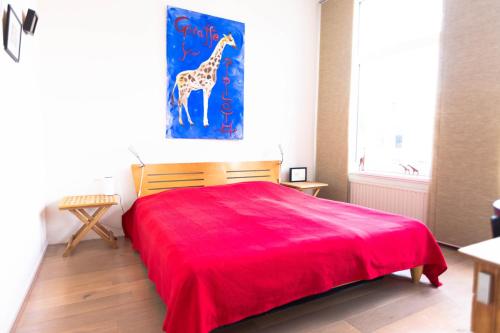 a bedroom with a red bed with a giraffe painting on the wall at B&B Brouwersvaart in Haarlem