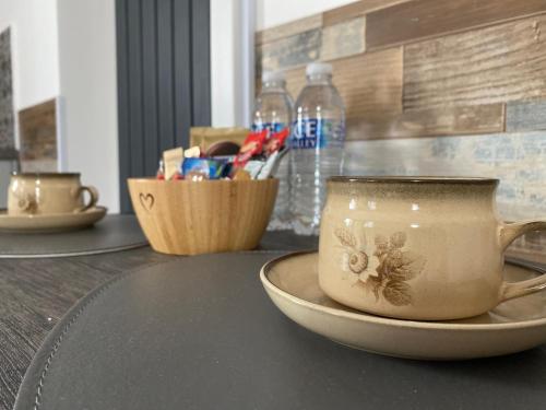 een beker op een bord op een tafel met waterflessen bij Cristina Modern in Horley