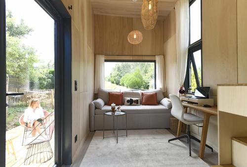 ヴェルトゥにあるLa tiny house de la Blandinièreのソファと窓のあるリビングルーム