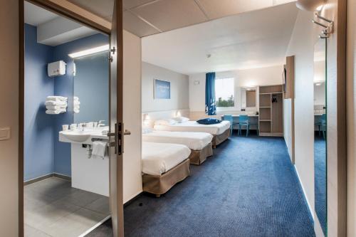 a hotel room with two beds and a sink at Ace Hôtel Toulouse Blagnac in Cornebarrieu