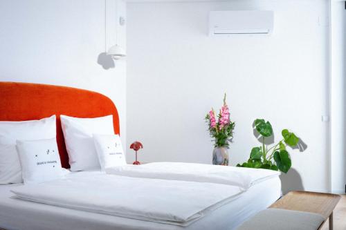 two beds with white sheets and flowers in a bedroom at Design-Apartment Olhão by Sisters of Paradise in Olhão