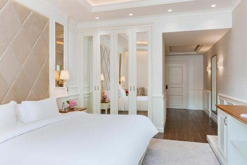 a white bedroom with a large bed and a hallway at Heritage Grand Perast By Rixos in Perast
