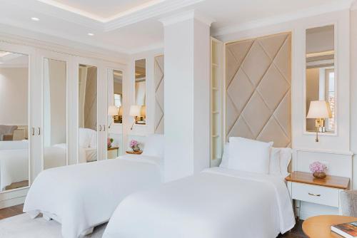 a white bedroom with two beds and a mirror at Heritage Grand Perast By Rixos in Perast