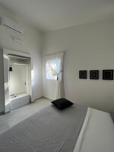 ein weißes Schlafzimmer mit einem Bett und einem Fenster in der Unterkunft Villa Giuliana Luxury Home: piscina, solarium, barbecue. A pochi passi dal mare in Fontane Bianche