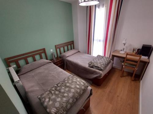 Habitación con 2 camas, mesa y ventana en Amplio apartamento en Sabiñánigo - Las Margas Pirineo Aragones, en Sabiñánigo