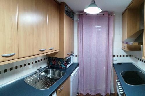 cocina con fregadero y cortina púrpura en Amplio apartamento en Sabiñánigo - Las Margas Pirineo Aragones, en Sabiñánigo