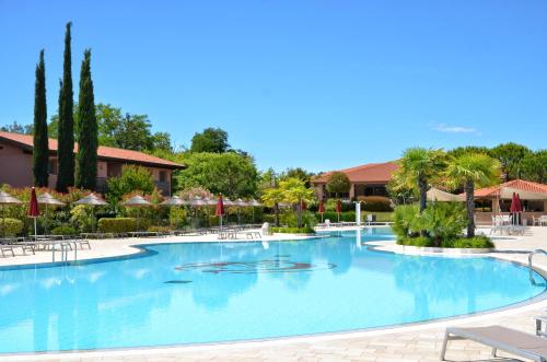 una gran piscina con sillas y sombrillas en un complejo en Green Village Eco Resort, en Lignano Sabbiadoro
