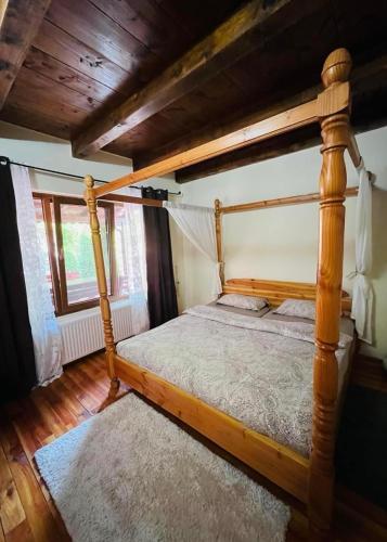 a wooden canopy bed in a room with a window at Casa Ana in Moneasa