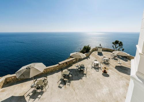 una vista aérea de un patio con mesas y sillas y el océano en Faro Punta Imperatore en Ischia