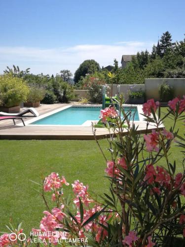 einen Pool im Garten mit rosa Blumen in der Unterkunft Logement spacieux agréable in Saint-Privat