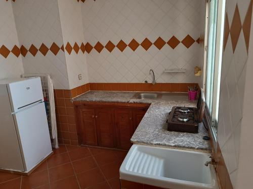 a kitchen with a sink and a white refrigerator at Residence Family OULANTI in Martil
