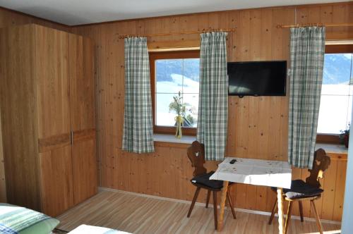 Zimmer mit einem Tisch, 2 Stühlen und einem TV in der Unterkunft Haashof in Vordergöriach