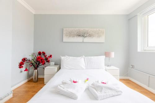 Un dormitorio blanco con una cama blanca con flores rojas en Cosy 3 Bed Flat Ideal for Trips to London en Londres