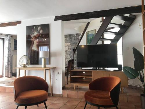 - un salon avec deux chaises et une télévision à écran plat dans l'établissement A l’ombre du Clocher, à Rochefort