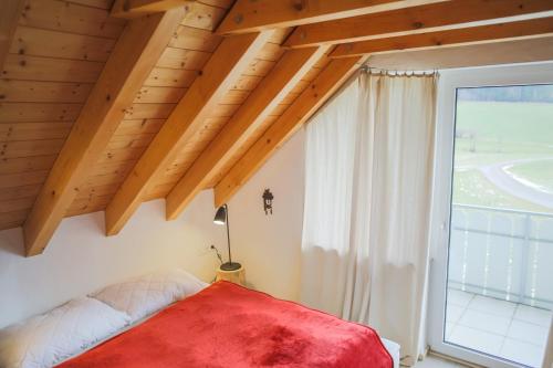 Schlafzimmer mit einem roten Bett und einem großen Fenster in der Unterkunft Kuckucksnest Schwärzenbach in Titisee-Neustadt