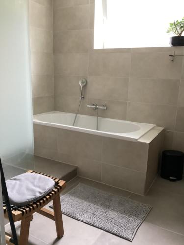 a bathroom with a bath tub and a chair at Good Life à Strasbourg in Strasbourg