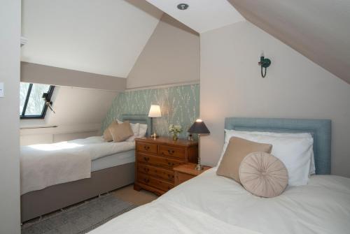 um quarto com 2 camas e uma cómoda com 2 candeeiros em School House em Malmesbury