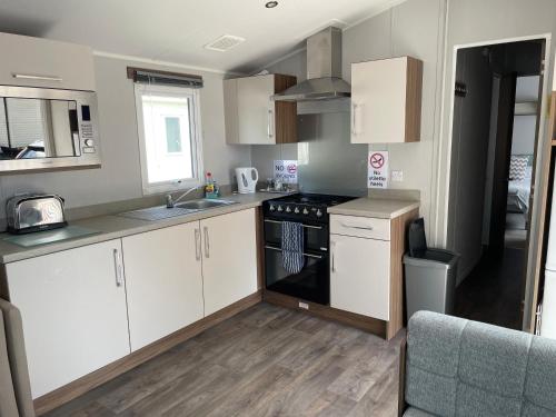 a kitchen with white cabinets and a stove top oven at Rockley Park Private Holiday Homes in Poole