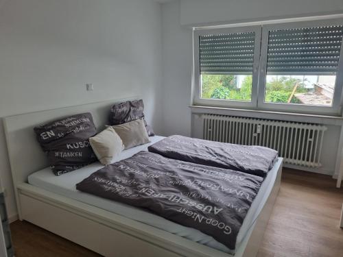 a bed with blankets and pillows on it with two windows at ~Ferienwohnung Sandhausen / HD~ in Sandhausen
