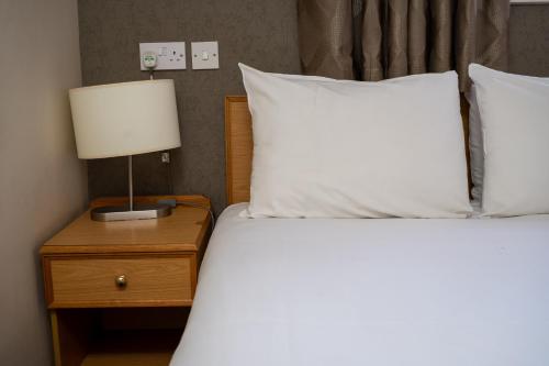a bed with white sheets and a lamp on a nightstand at Old Grey Mare Inn by Greene King Inns in Hull