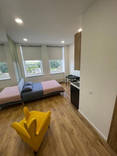 ein Wohnzimmer mit einem Sofa und einem gelben Stuhl in der Unterkunft Airport Apartment 22 Self Check-In in Vilnius