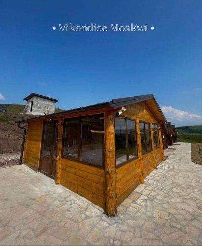 a small wooden building with windows on a stone ground at Vikendice Moskva Uvac in Sjenica