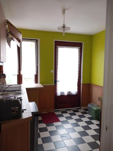 a kitchen with yellow and green walls and a door at Au coteau des Thermes in Saint-Honoré-les-Bains