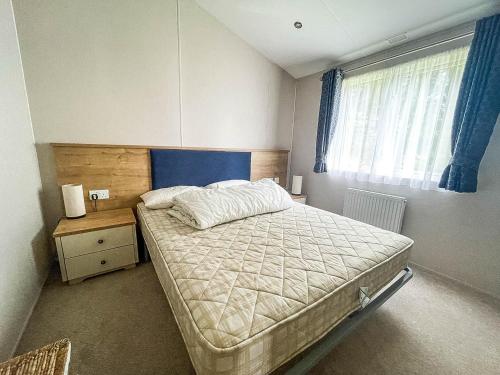 a bedroom with a bed and a window at Beautiful Lodge With Decking At Breydon Water Park In Norfolk Ref 10022b in Belton