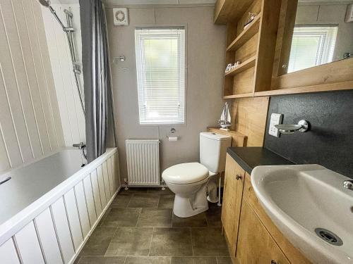 a bathroom with a toilet and a tub and a sink at Beautiful Lodge With Decking At Breydon Water Park In Norfolk Ref 10022b in Belton