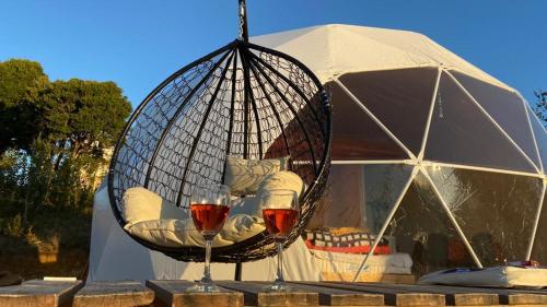 a swing with a glass of wine in front of a tent at Domo con tinaja, Estaquilla in Los Muermos