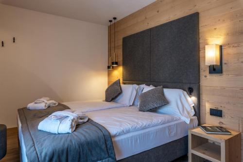 a hotel room with two beds with towels on them at Hotel Meida in Pozza di Fassa