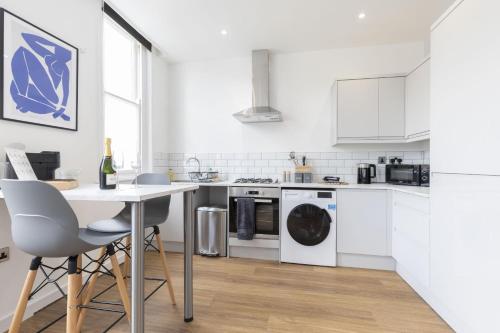 a kitchen with white appliances and a table and chairs at Beautifully presented newly renovated city-centre apartment in Cheltenham in Cheltenham